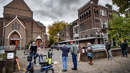 Ouderen in Nijmegen wachten voor het kerkgebouw waar ze dit jaar hun griepprik krijgen