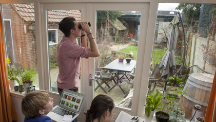 Drie jongeren tellen vanuit hun kamer de vogels in de tuin voor de Nationale Tuinvogeltelling.