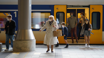 Mensen met mondkapjes op stappen uit de trein