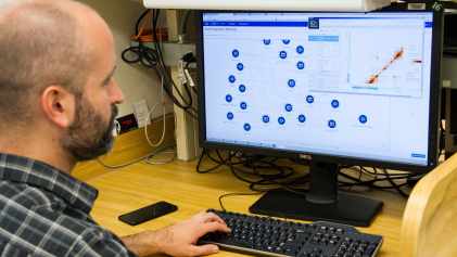 Een man analyseert grote hoeveelheden data op zijn computer voor kankeronderzoek