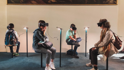 4 personen zitten met een VR bril op voor een kunstwerk