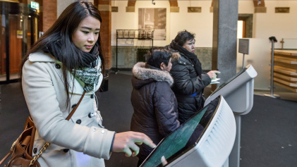 Een mevrouw trekt een nummer voor de balie van het Stadskantoor in Rotterdam
