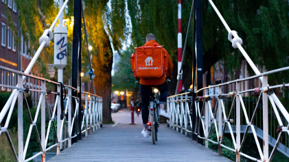 Een bezorger van Thuisbezorgd fietst over een brug