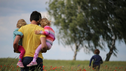 Een vader loopt met zijn kinderen door een bloemenveld