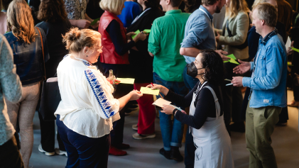 Twee deelnemers aan het macht-symposium wisselen gele briefjes uit.