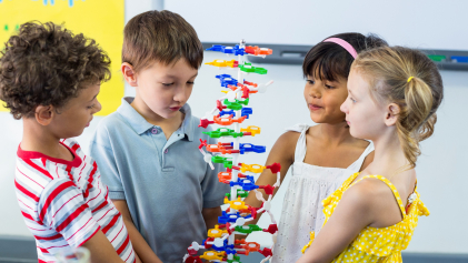 Vier kinderen kijken naar een plastic DNA-model