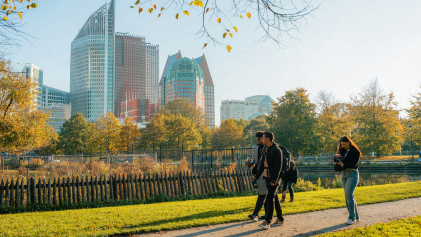 Mensen wandelen in park met op achtergrond skyline Den Haag