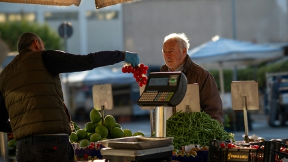 Marktkoopman overhandigt tomaten, koper twijfelt