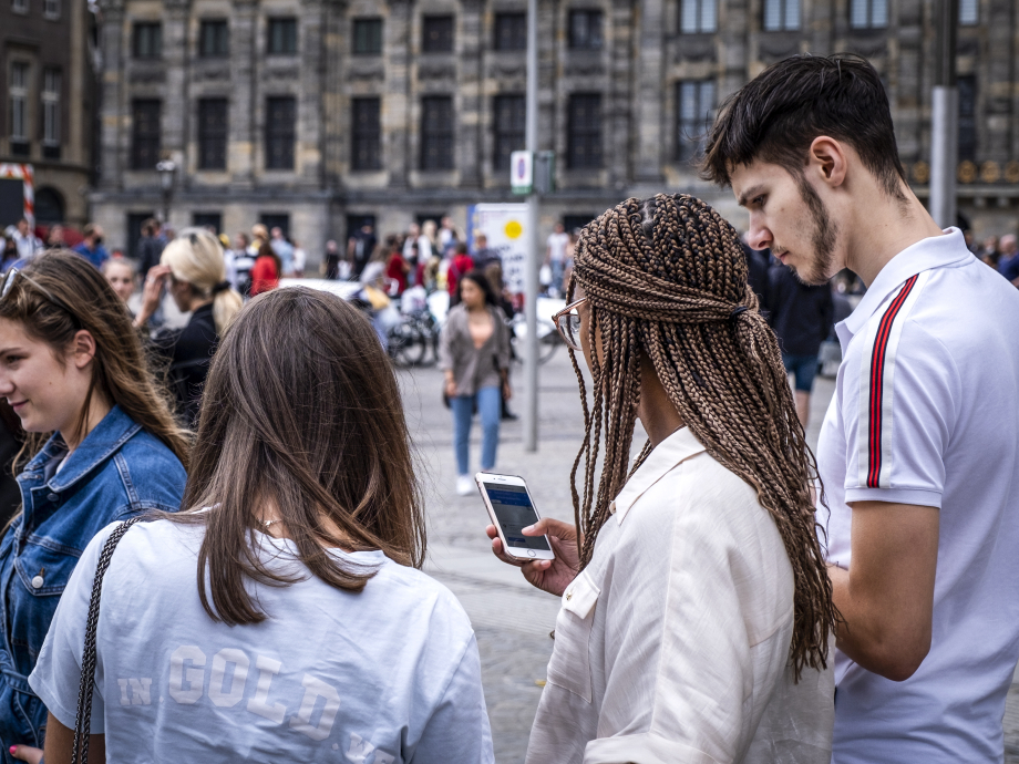 Mensen op straat in Amsterdam die op hun telefoon kijken. Coverfoto rapport initiatieven voor digitale democratie op nationaal niveau.