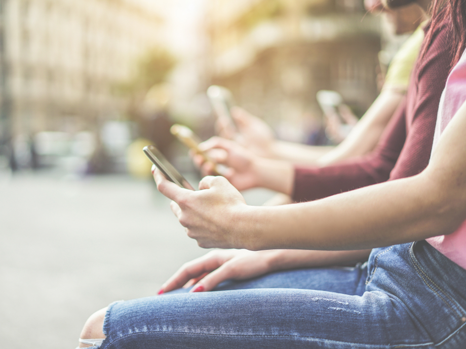 Twee mensen kijken op een bankje op straat op hun telefoon