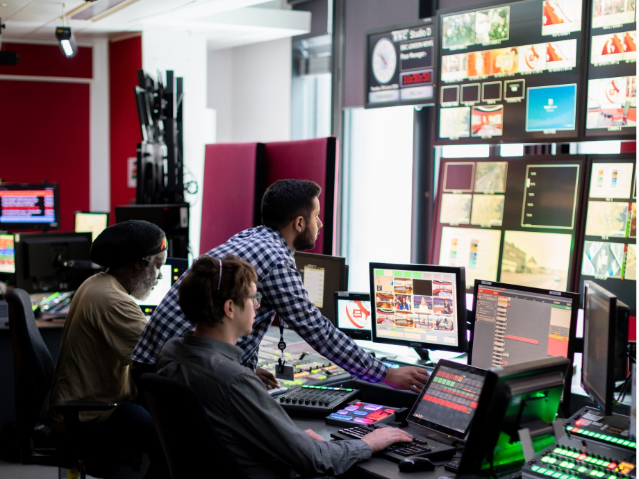 Medewerkers kijken in de control room mee op de verschillende schermen