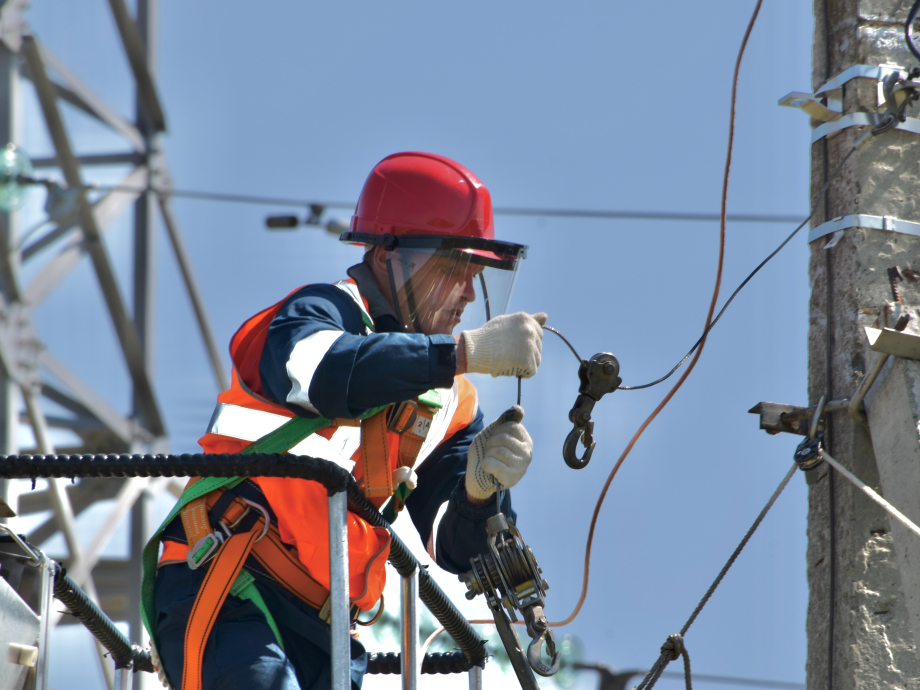 Een man aan het werk bij een electriciteitspaal