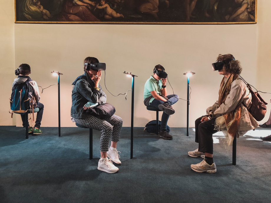 4 personen zitten met een VR bril op voor een kunstwerk