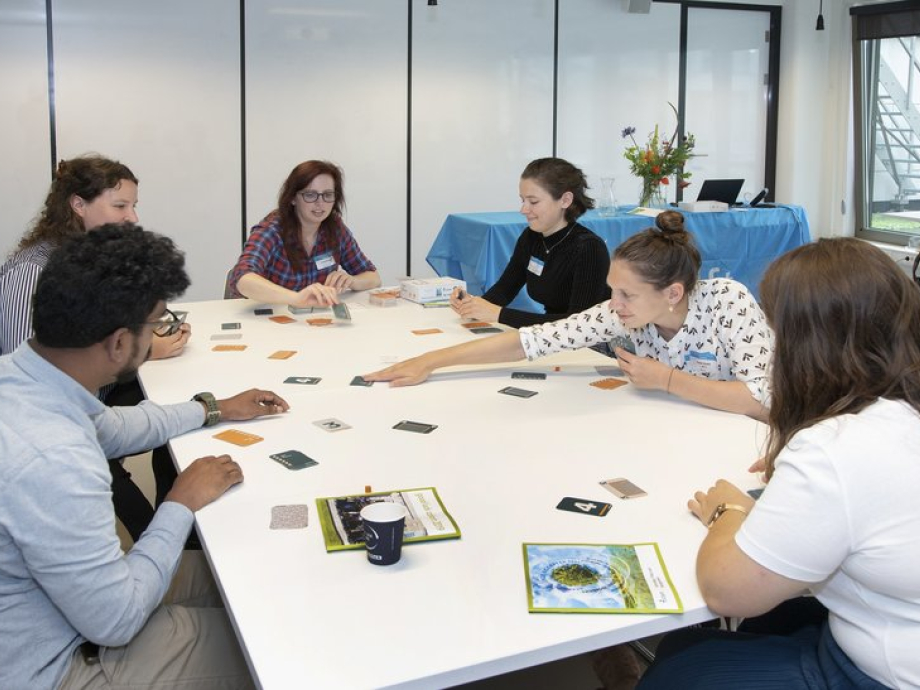 Spelers zitten aan een tafel Cards for Biosafety te spelen