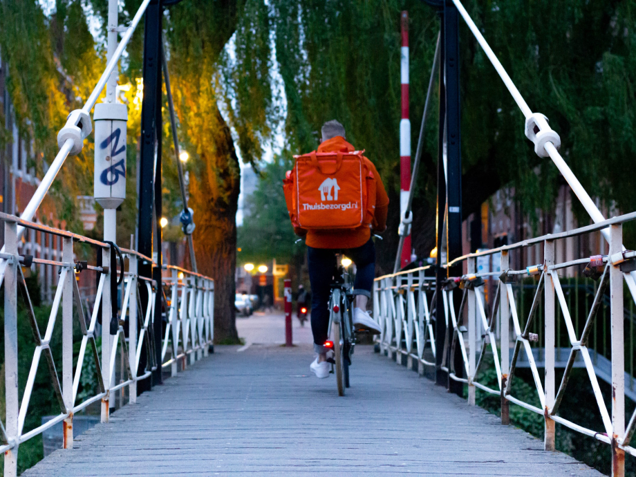 Een bezorger van Thuisbezorgd fietst over een brug