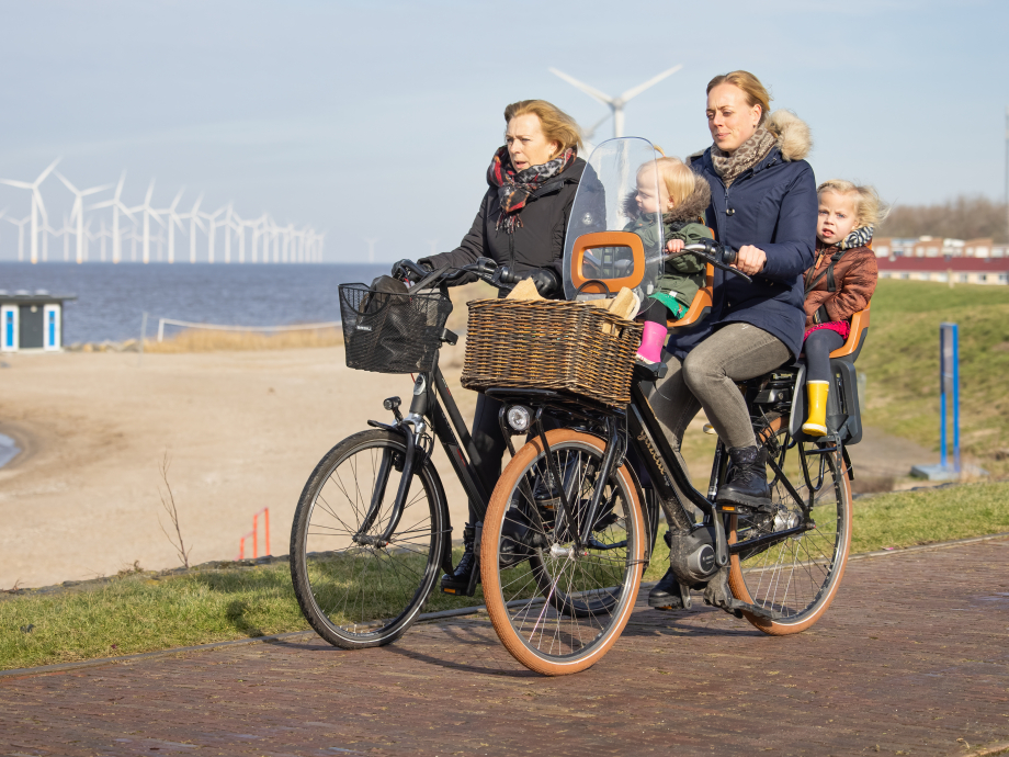 Fietsers langs het IJsselmeer met op de achtergrond windmolens