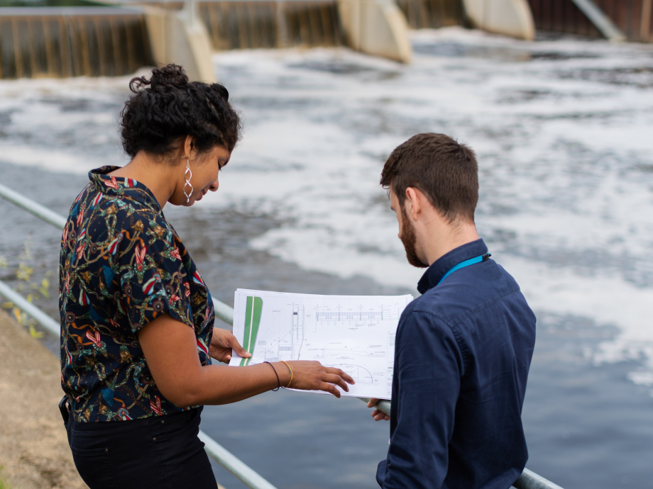Twee wetenschappers staan naast het water voor hun onderzoek naar overstromingsmanagement