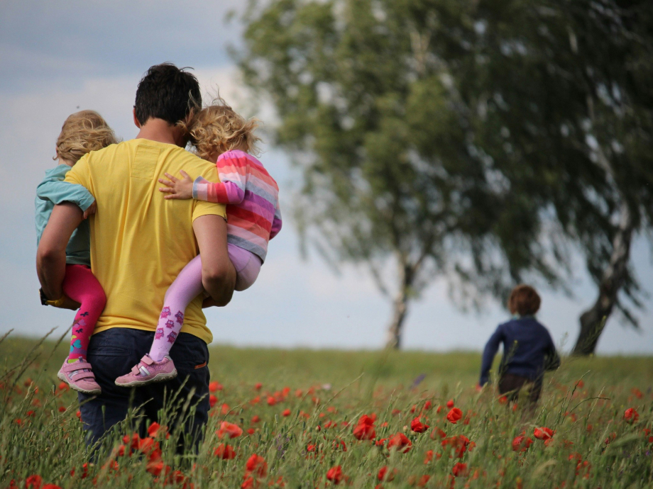 Een vader loopt met zijn kinderen door een bloemenveld