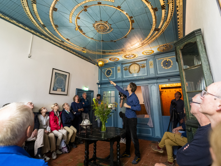 Bezoekers van het Eise Eisinga Planetarium krijgen uitleg over de werking ervan.