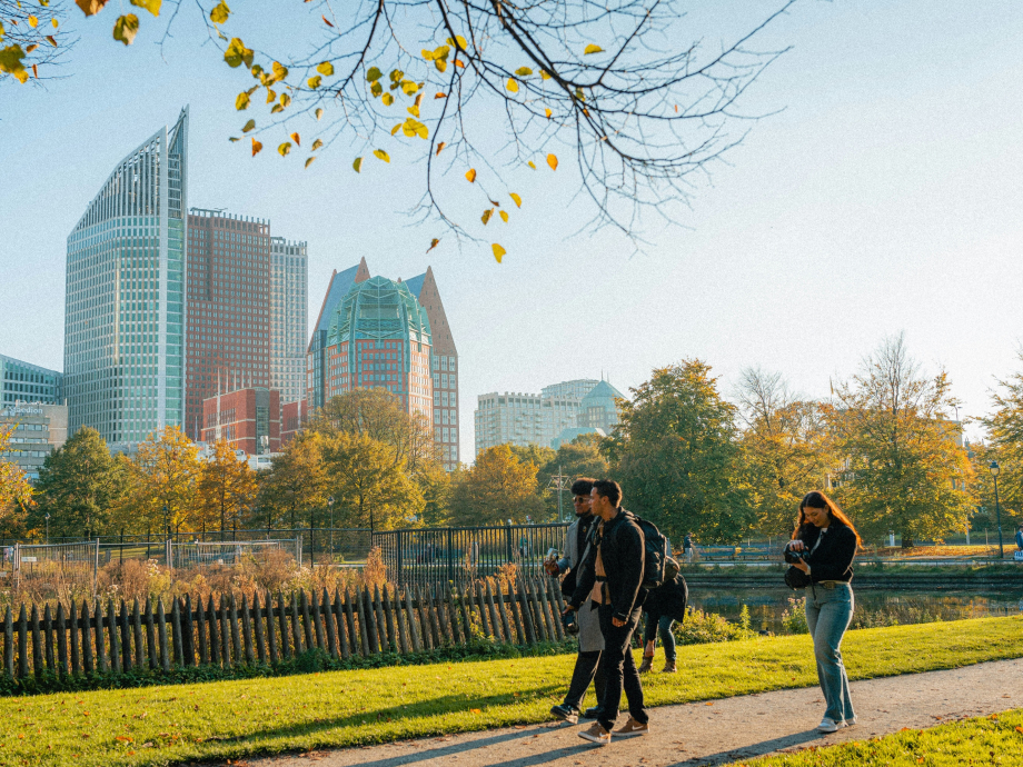 Mensen wandelen in park met op achtergrond skyline Den Haag