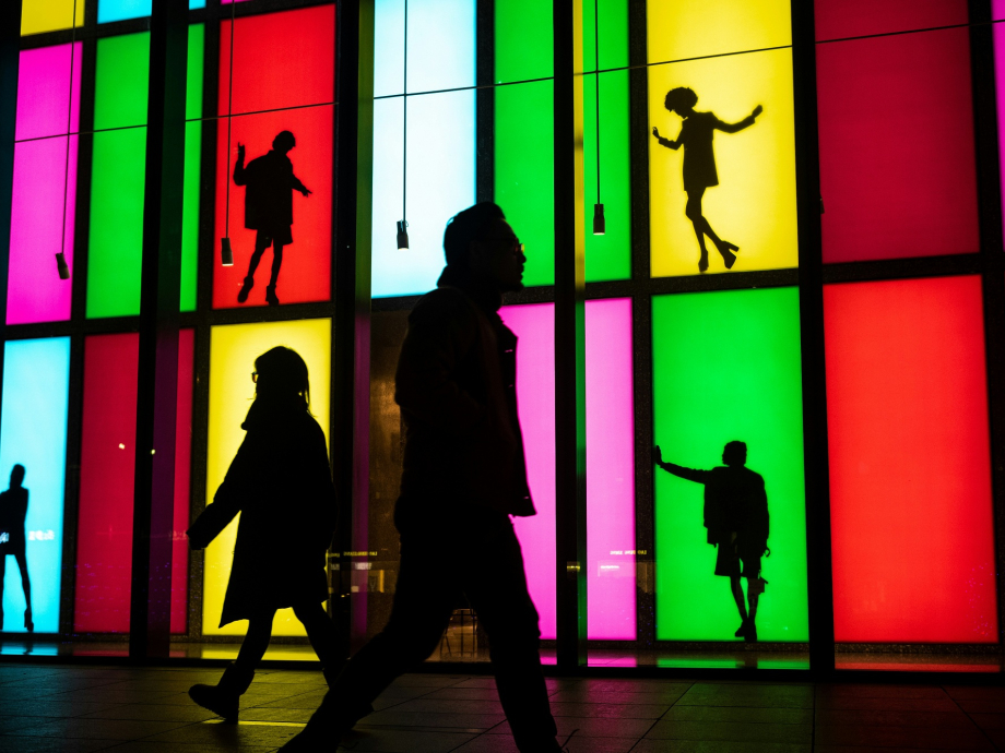 Mensen lopen langs kunstwerk van etalages met felle kleuren