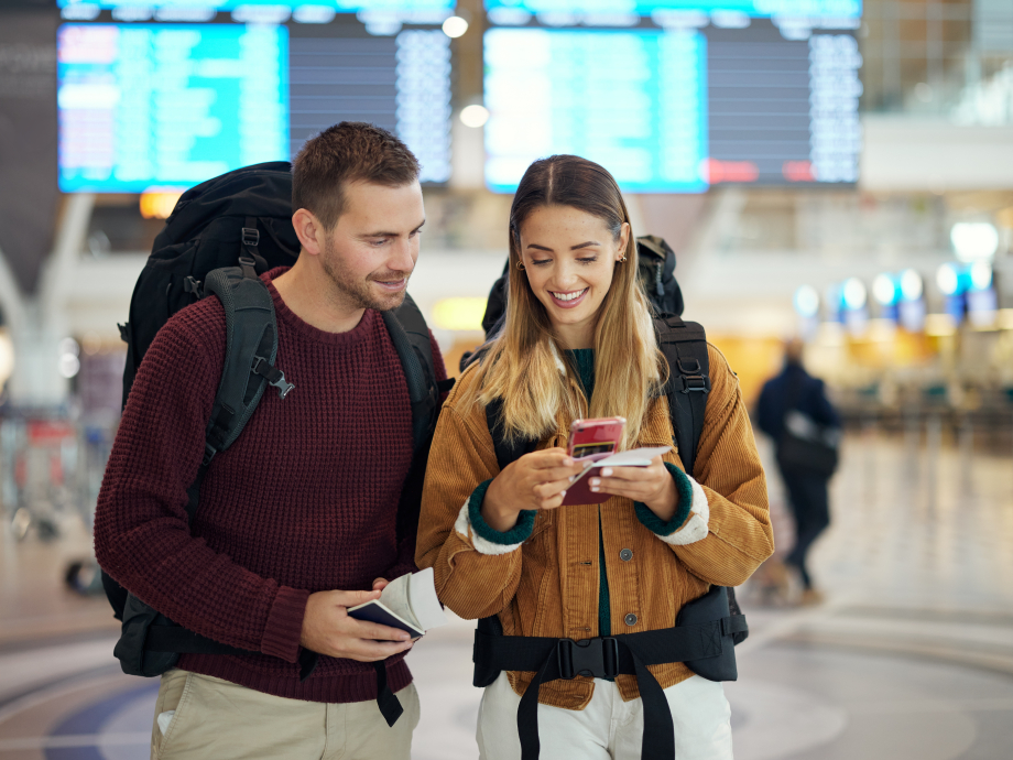 Twee personen op reis met een ticket in hun hand kijken op hun telefoon