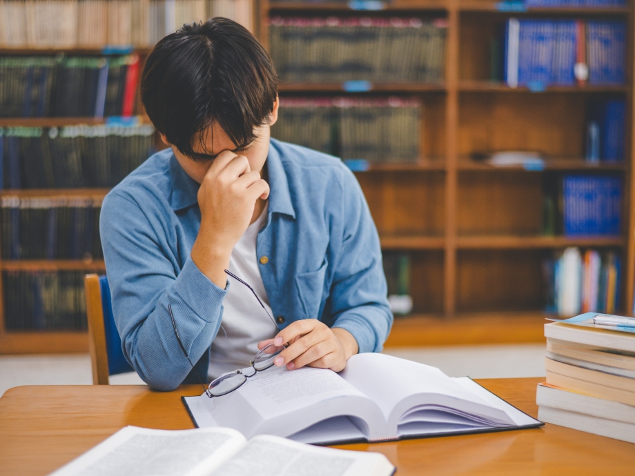 Boekenkast met vermoeide student 