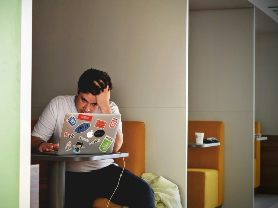Man met laptop in hokje en hand in het haar