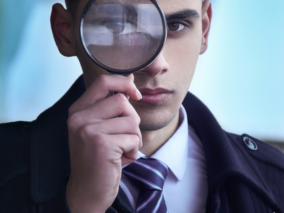 Jongen die een vergrootglas voor zijn oog houdt 