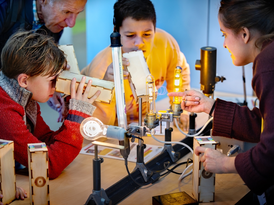 Kinderen kijken naar het lichtspectrum van verschillende lampen tijdens het Weekend van de Wetenschap. Foto: Digidaan