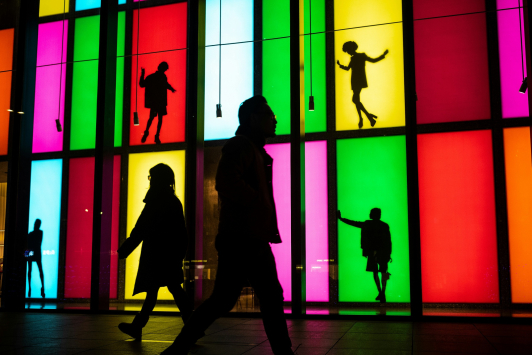 Mensen lopen langs kunstwerk van etalages met felle kleuren