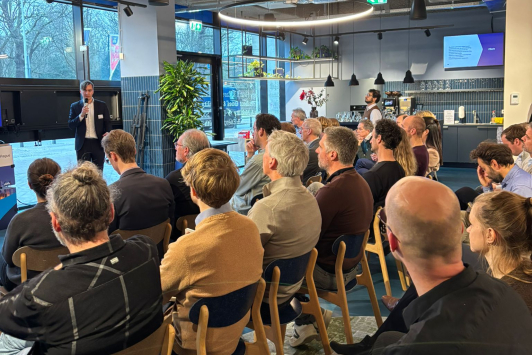 Twintig personen in een zaal kijken naar een scherm