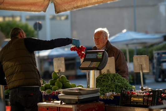 Marktkoopman overhandigt tomaten, koper twijfelt
