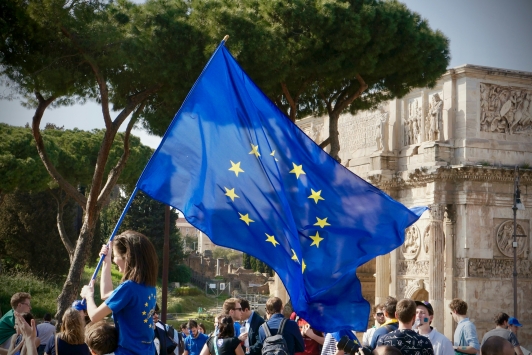 Een meisje houdt temidden van allerlei mensen een Europese vlag vast. 